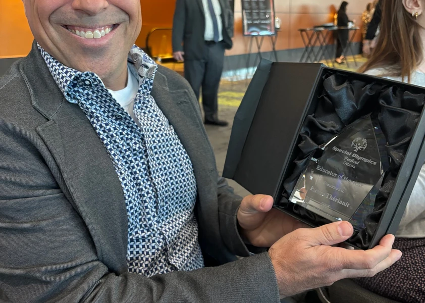 Pierre Thériault tient son trophée d’Éducateur de l’année des Olympiques spéciaux Ontario – Ottawa et sourit à l’objectif.