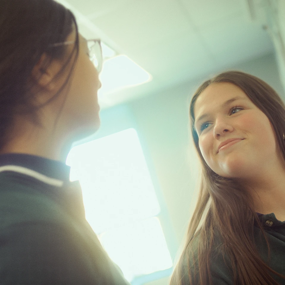 Deux élèves qui se regardent souriantes arborant l'uniforme de l'école